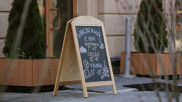 SOCHI, RUSIA - 8 DE ABRIL DE 2016: Menú callejero escrito a mano en pizarra en la puerta principal del restaurante. Café. Cena. — Vídeo de stock