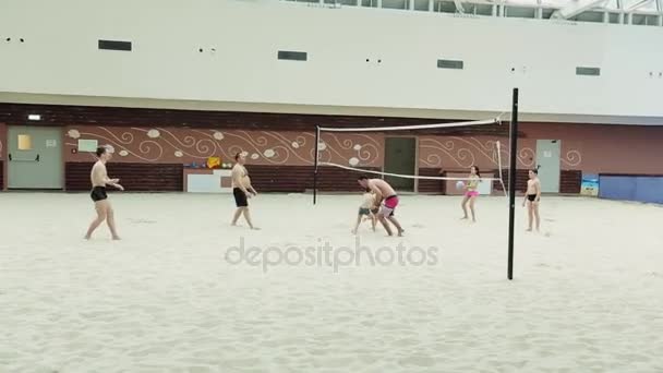 Sochi, Rusland - 8 April 2016: Mensen spelen volleybal op kunstmatige zand strand onder dak van het gebouw. Kinderen — Stockvideo