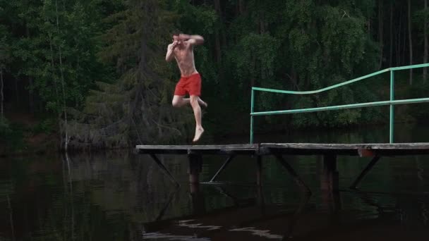 Giovane uomo saltare in acqua del lago con go pro fotocamera in mano. Estate. Capovolgimenti — Video Stock