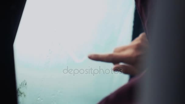 Mann zeichnet mit einem Finger Häkchen am Autofenster. Regenwetter draußen. Tropfen — Stockvideo