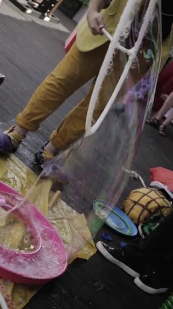 SAINT PETERSBURG, RUSSIA - AUGUST 18, 2016: Animator in clown costume make big soap bubble on terrace of restaurant. — Stock Video