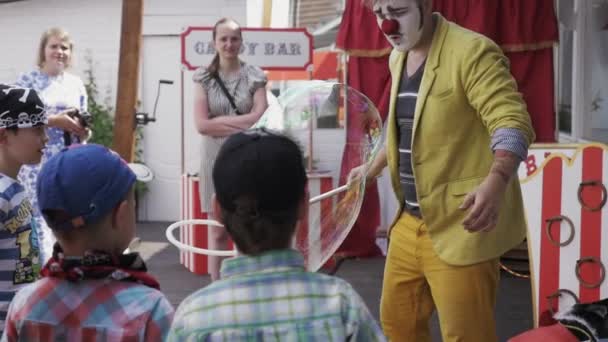 СЕНТ-ПЕТЕРБУРГ, РОССИЯ - 18 августа 2016 года: Клоун делает мыльный пузырь на террасе ресторана. Развлекательное мероприятие. Дети — стоковое видео
