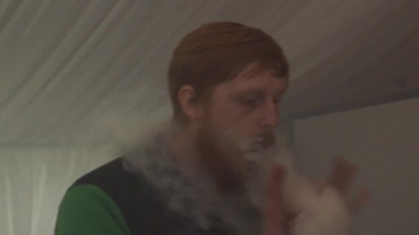 САЙНТ-ПЕТЕРБУРГ, РОССИЯ - 28 мая 2016 года: Бородатый мужчина выдыхает пар из электронной сигареты на фестивале. Конкурс. Vaper — стоковое видео