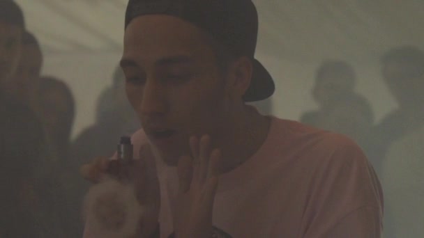 Saint petersburg, russland - 28. Mai 2016: Junge mit Mütze atmet Ring von Dampf aus elektronischer Zigarette aus. Dampf ab. Publikum. — Stockvideo
