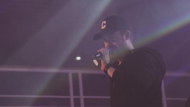Petrohrad, Rusko - 28 května, 2016: Mladý hostitel s mikrofonem na pódiu v nočním klubu. Elektronická cigareta v ruce. — Stock video