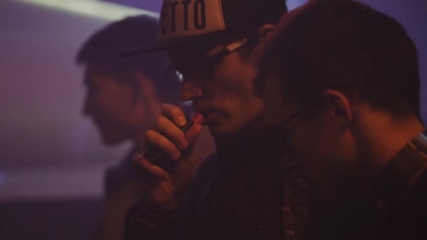 Санкт-Петербург, Російська Федерація - 28 травня 2016: Молоді хлопці курити електронну сигарету в нічному клубі. Партія. Точкові світильники. Vaper — стокове відео