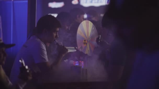 SAN PETERSBURG, RUSIA - 28 DE MAYO DE 2016: Los hombres fuman cigarrillos electrónicos en el club nocturno del stand. Vapers. Proyectores . — Vídeo de stock