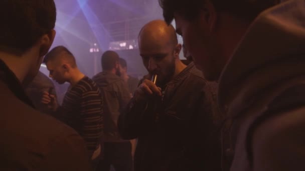 SAINT PETERSBURG, RÚSSIA - 28 de maio de 2016: Homens fumam cigarros eletrônicos em boate. Festa. Holofotes. Ceifeiras . — Vídeo de Stock