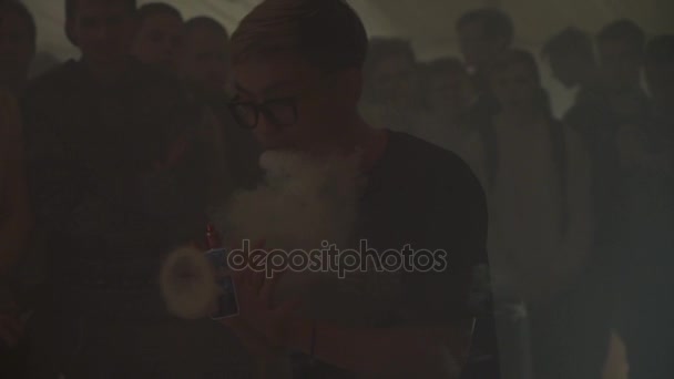 SAN PETERSBURG, RUSIA - 28 DE MAYO DE 2016: Niño asiático en gafas exhala anillo de vapor del cigarrillo electrónico. Desafío — Vídeos de Stock