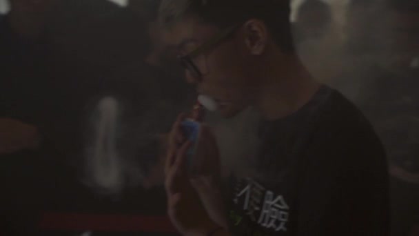 Saint petersburg, russland - 28. mai 2016: asiatischer junge in brille atmet wolke von dampf aus elektronischer zigarette. Herausforderung — Stockvideo