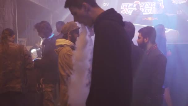 SAINT PETERSBURG, RUSSIA - 28 MAGGIO 2016: Ragazzo fuma sigaretta elettronica in discoteca tra le altre persone. Sotto i riflettori. Vaper — Video Stock