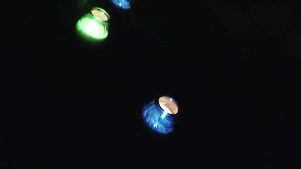 SAINT PETERSBURG, RÚSSIA - 17 de agosto de 2007: Ver velas acesas ficar em castiçais coloridos no asfalto à noite. Gren, azul, amarelo. Escuridão — Vídeo de Stock