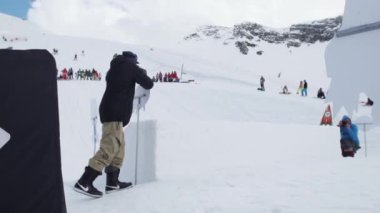 Soçi, Rusya - 7 Nisan 2016: Sıçrama tahtası binmek peluş takım elbise genç kayakçı. Karton nesneler. Kameraman.