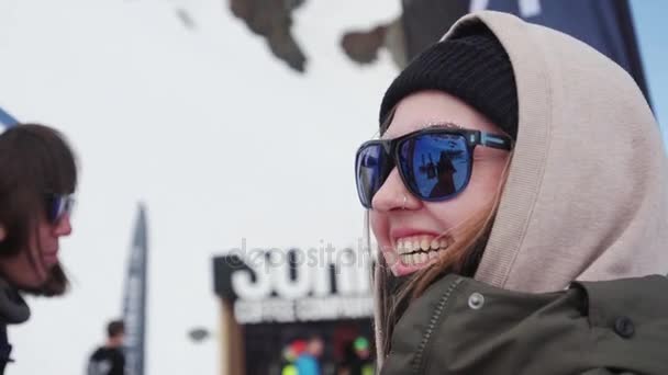 ソチ, ロシア連邦 - 2016 年 4 月 7 日: 少女スキー場でサングラスを笑う私。面白いキャップの女性。エンカンプします。イベント. — ストック動画