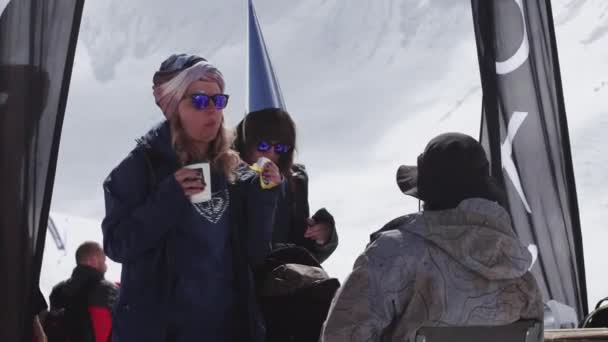 Σότσι, Ρωσία - 7 Απριλίου 2016: Κορίτσι σε γυαλιά ηλίου και το κορίτσι σε αστεία ΚΓΠ ποτό καφέ σε encamp στο χιονοδρομικό κέντρο. — Αρχείο Βίντεο