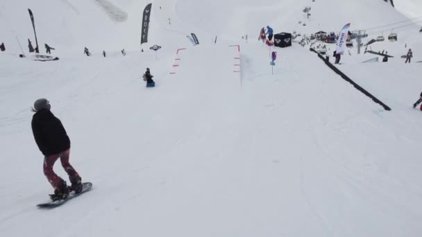 SOCHI, RUSIA - 7 DE ABRIL DE 2016: Estación de esquí. Paseo adolescente snowboarder en trampolín. Soleado. Objeto cósmico de cartón — Vídeos de Stock