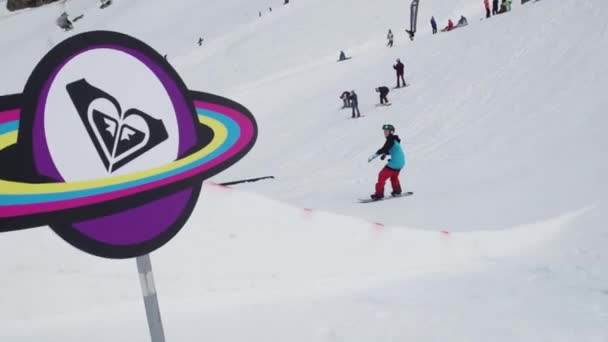 SOCHI, RUSIA - 7 DE ABRIL DE 2016: Estación de esquí. Adolescente snowboarder saltar en el trampolín. Objetos cósmicos de cartón. Sol — Vídeos de Stock