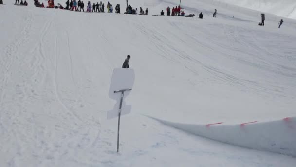 СОЧИ, РОССИЯ - 7 апреля 2016 года: Подросток катается на сноуборде на трамплине. Санни. Картонные космические объекты. Люди — стоковое видео