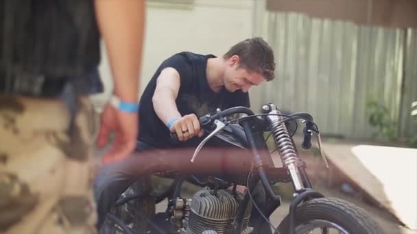 Junger Mann im Hemd am selbstgebauten Motorrad. viele verschiedene ungewöhnliche Details. Sommertag. — Stockvideo