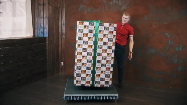 Tovenaar in rood polo shirt in studio Toon truc maakt grote aanwezig doos zweven — Stockvideo