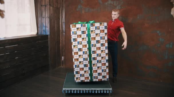 Tovenaar in rood shirt in studio gebruik telekinese maakt grote aanwezig doos zweven — Stockvideo