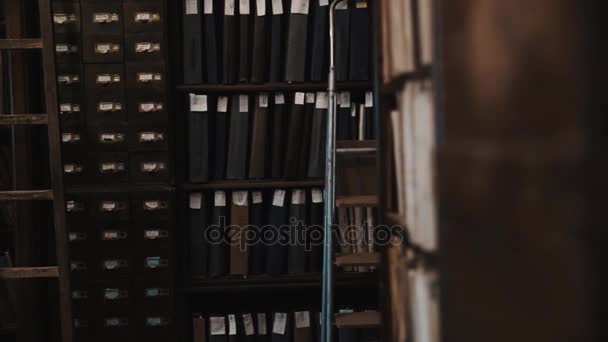 Dolly shot interior of old archive bookshelves with document folders — Stock Video