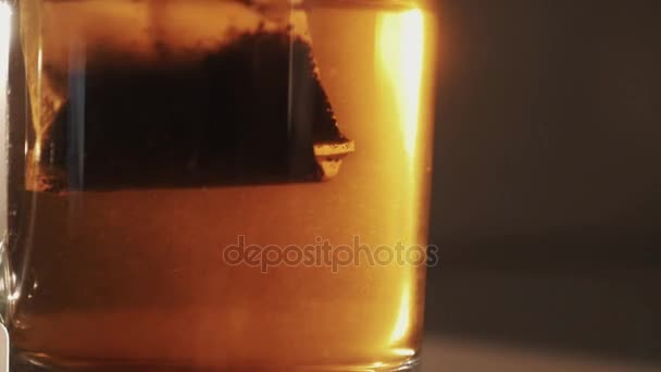 Slowmotion fermer sac de thé tiré et secoué dans un verre transparent d'eau — Video