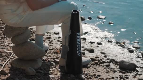 Filmový režisér megafon stojícího na břehu jezera poblíž muž v bílých kalhotách — Stock video