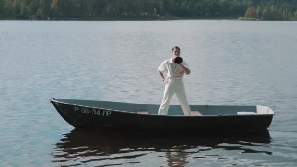 Man in hair net and white clothes standing on boat yelling into megaphone — Stock Video