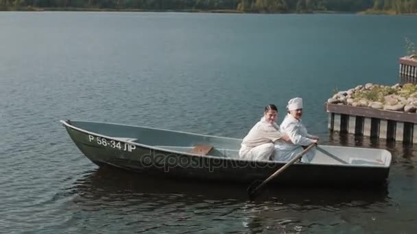 純の髪の男と湖でボートで看護師は夏の晴れた日に漕ぐオールを使用します。 — ストック動画