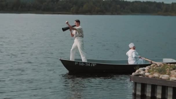 Nurse paddling boat on lake, man in white clothes commands into speaker — Stock Video