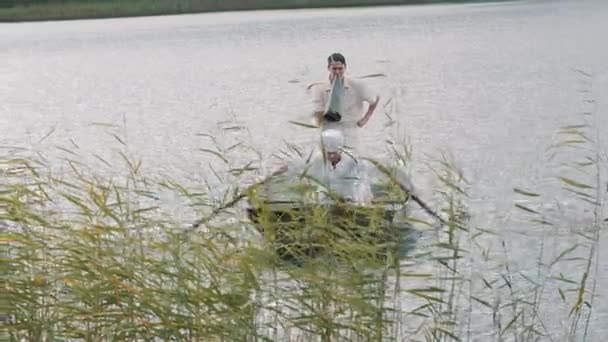 Nurse rowing boat on lake, man in white clothes commands into megaphone — Stock Video