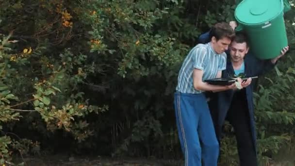 Mannen komen schudden struik met Prullenbak kunnen en Tablet PC controleren op zomerdag — Stockvideo