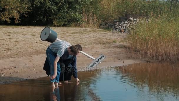 Два хлопці стоять на березі води, дивляться вниз, розмовляють і починають кричати літній день — стокове відео