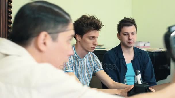 Homme en filet de cheveux utiliser un vieil appareil photo 8mm dans le bureau tirant sur deux travailleurs — Video