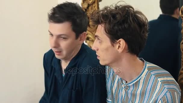 Dos hombres preocupados se sientan en la sala blanca en el espejo hablando — Vídeo de stock
