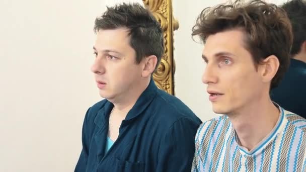 Dos hombres preocupados se sientan en la sala blanca en el espejo discutiendo — Vídeo de stock