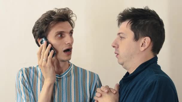 Dois homens preocupados em pé no salão branco falando no telefone celular — Vídeo de Stock