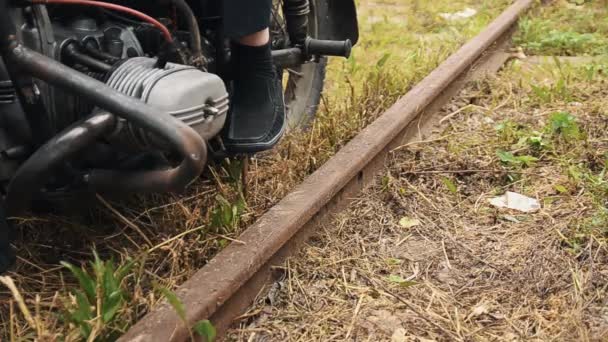 Mann in maßgeschneiderter Hose zieht Motorrad auf Bahngleisen aus — Stockvideo