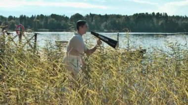 Saç filesi film yapımcısı kamış Gölü kıyısında ayakta ve hoparlörün içine bağırma