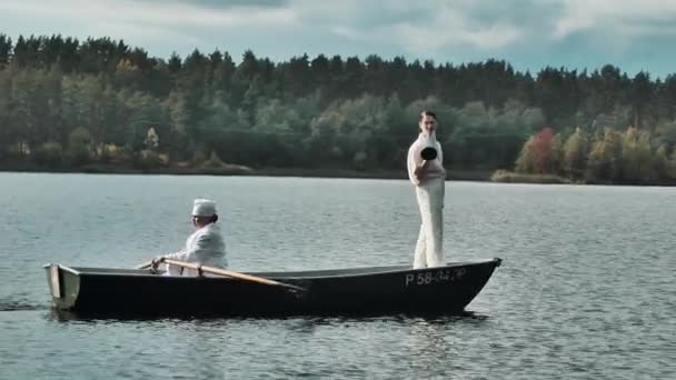 Infermiera barca a remi sul lago, uomo in abiti bianchi comanda in megafono — Video Stock