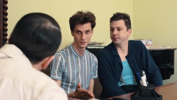Мужчина в сетке для волос сердится, споря с двумя посетителями на встрече в офисе — стоковое видео