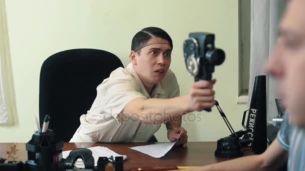Человек в сетке для волос использование ретро 8 мм камера в офисе съемки посетителя — стоковое видео