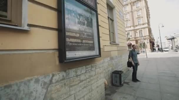 Sint-Petersburg, Rusland - 23 juni 2016: Tracking shot man smking sigaret op hoek van de oude architectuur stijl gebouw — Stockvideo