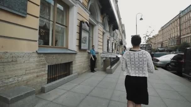 SAINT PETERSBURG, RUSSIE - 23 JUIN 2016 : Plan d'une femme marchant dans la rue de la vieille ville, qui arrive aux portes en bois — Video