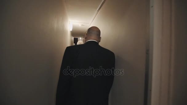 SAN PETERSBURG, RUSIA - 23 DE JUNIO DE 2016: Tracking shot of big bald man in black jacket walking throgh narrow corridor — Vídeos de Stock