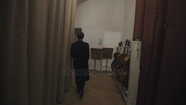 САЙНТ-ПЕТЕРБУРГ, РОССИЯ - 23 июня 2016 года: Отслеживание застреленного человека в черном пальто, идущего за сценой в концертном зале — стоковое видео