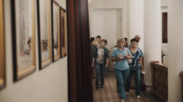 Sankt Petersburg, Ryssland - 23 juni 2016: Människor som vandrar längs korridoren i klassisk stil interiör med bilder på väggen — Stockvideo