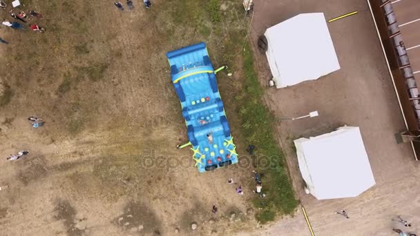 SAINT PETERSBURG, RUSSIE - 30 JUILLET 2016 : Un homme nu en haut d'un plan aérien saute sur un parcours d'obstacles gonflable bleu sur sable — Video