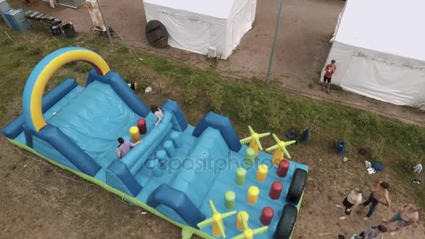 SAINT PETERSBURG, RUSSIA - JULY 30, 2016: Aerial top shot women jumping on blue inflatable obstacle course on sand — Stock Video